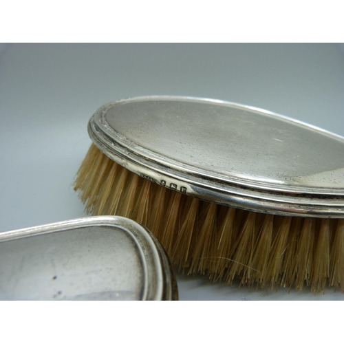 868 - A silver backed mirror and two brushes