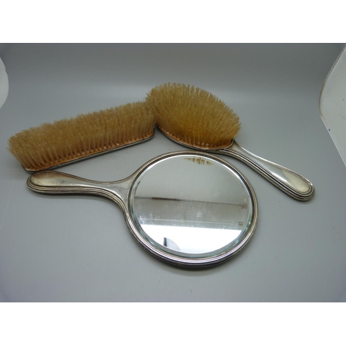 868 - A silver backed mirror and two brushes