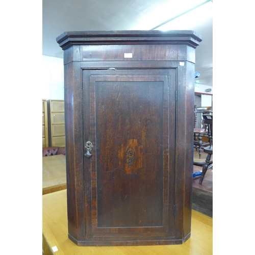 185 - A George III inlaid oak splay front wall hanging corner cupboard