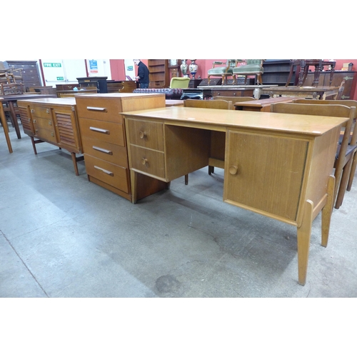 83 - A Meredew walnut desk, a teak chest of drawers and sideboard, a/f