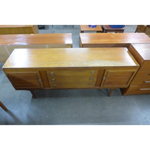 83 - A Meredew walnut desk, a teak chest of drawers and sideboard, a/f