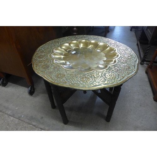 168 - An Indian carved wood and brass topped folding occasional table