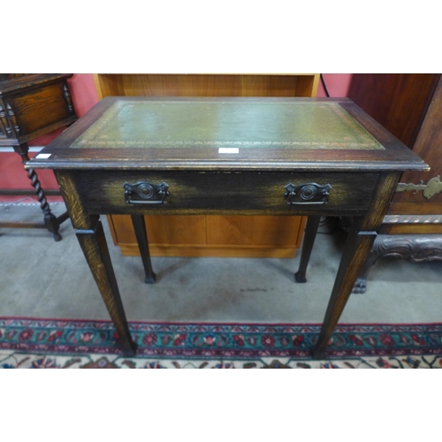 85 - An Arts and Crafts oak and green leather topped single drawer writing table