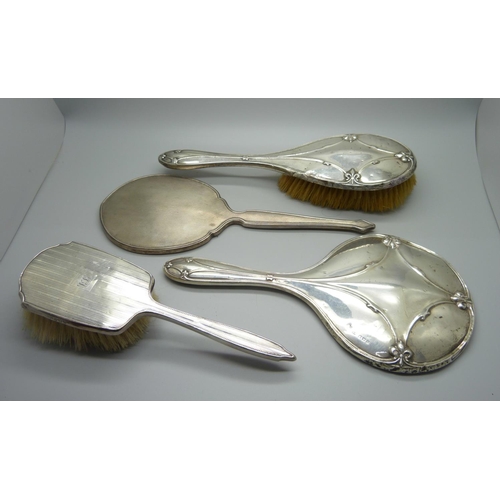 853 - A silver backed mirror, two silver backed brushes, a/f, and a silver mirror back for scrap