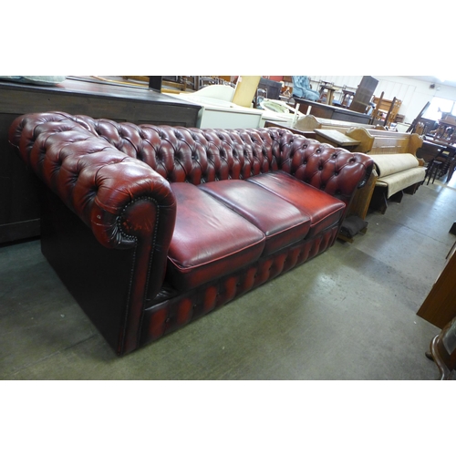 171 - An oxblood red leather three seater Chesterfield sofa