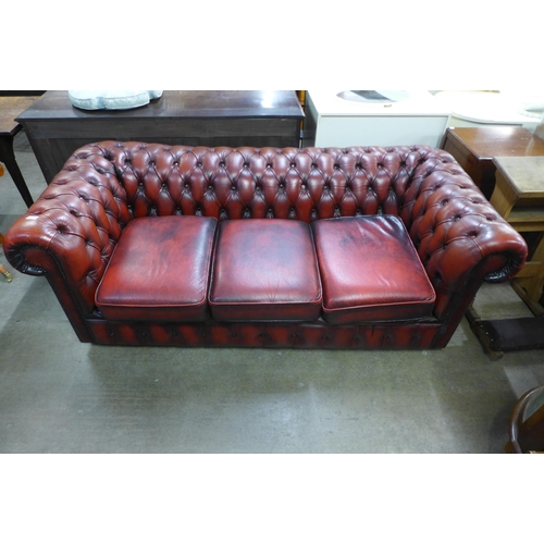 171 - An oxblood red leather three seater Chesterfield sofa