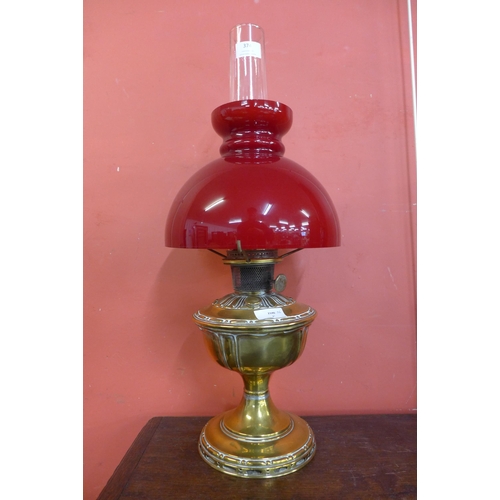 374 - A Victorian brass oil lamp with red glass shade ( converted to electric)