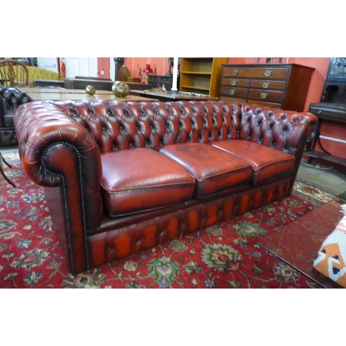 59 - An oxblood red leather three seater Chesterfield settee