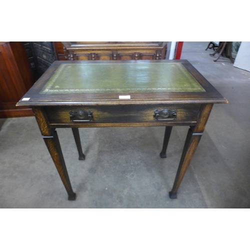 77 - An Arts and Crafts oak and green leather topped single drawer writing table