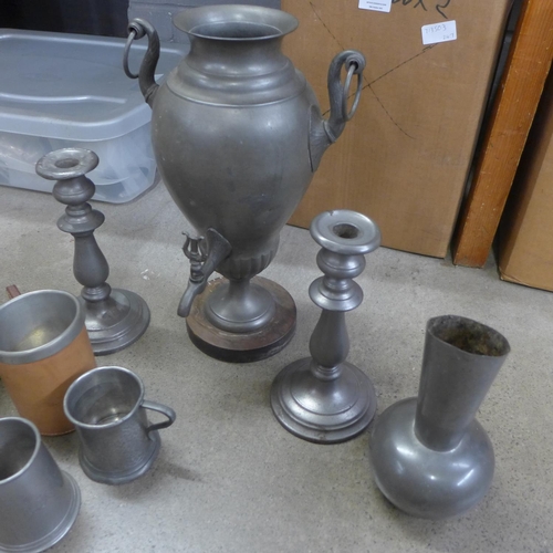 823 - A collection of pewter tankards, a pair of pewter candlesticks, a large urn and a jug