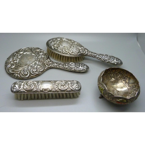 874 - A silver backed mirror and two brushes and a white metal and enamel pot