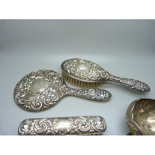 874 - A silver backed mirror and two brushes and a white metal and enamel pot