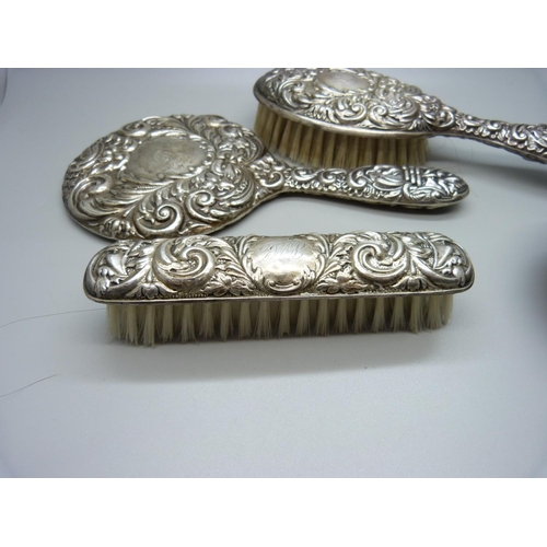 874 - A silver backed mirror and two brushes and a white metal and enamel pot