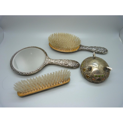 874 - A silver backed mirror and two brushes and a white metal and enamel pot