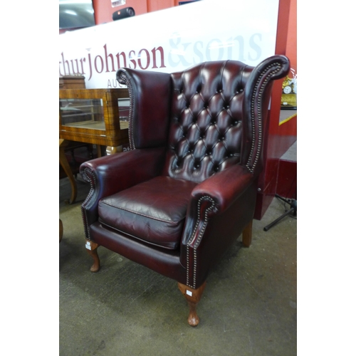 12 - An oxblood red leather Chesterfield wingback armchair