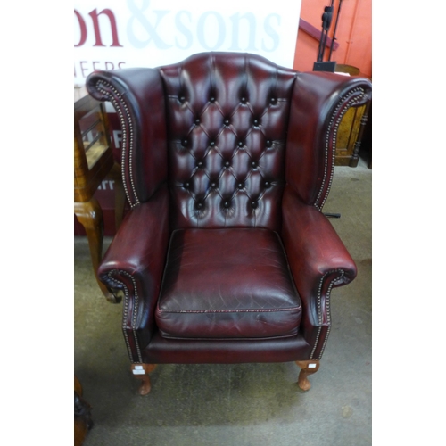 12 - An oxblood red leather Chesterfield wingback armchair