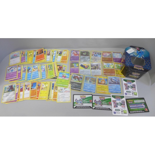 666 - A Pokemon collectors tin containing four rare holographic cards with protective sleeves, ten reverse... 