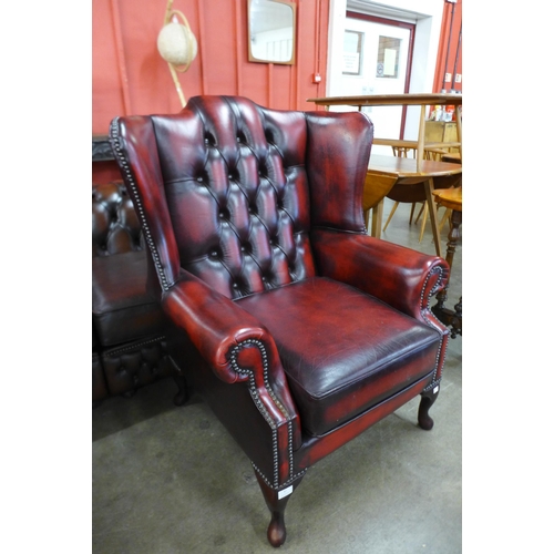 87 - An oxblood red leather Chesterfield wingback armchair