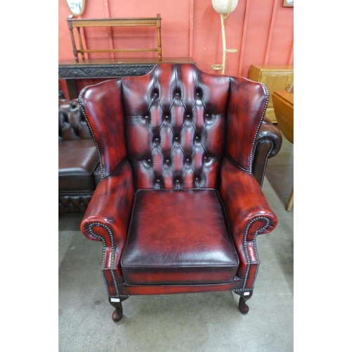 87 - An oxblood red leather Chesterfield wingback armchair