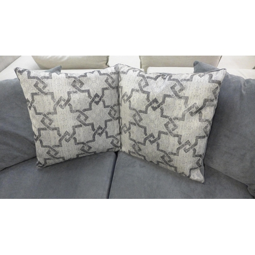 1412 - A grey upholstered three seater sofa with patterned cushions and footstool