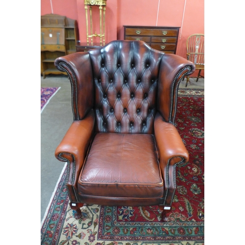 82 - An oxblood red leather wingback armchair