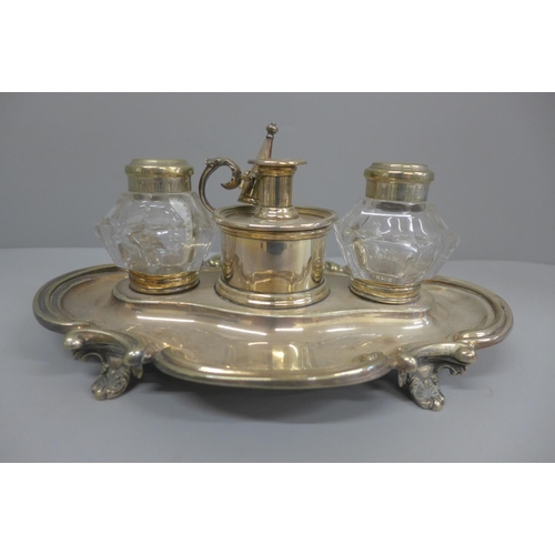 618 - A silver plated ink stand with two glass  inkwells and a small chamber stick, with engraving dated 1... 