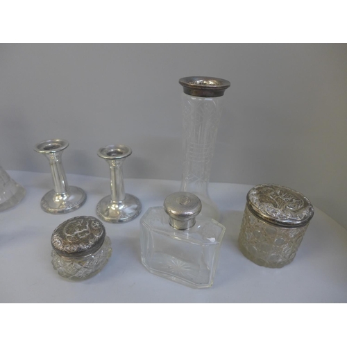 825 - A collection of silver topped and mounted glass jars and bottles, and a pair of silver candlesticks,... 