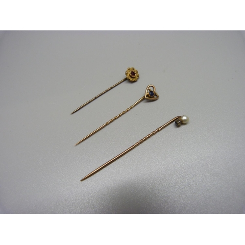 942 - Three stick pins, two marked 9ct and one set with an old cut diamond and a pearl, total weight 3.2g