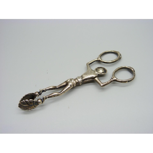 1005 - A pair of novelty silver sugar nips of a harlequin suspended by two coiled snakes which form the han... 