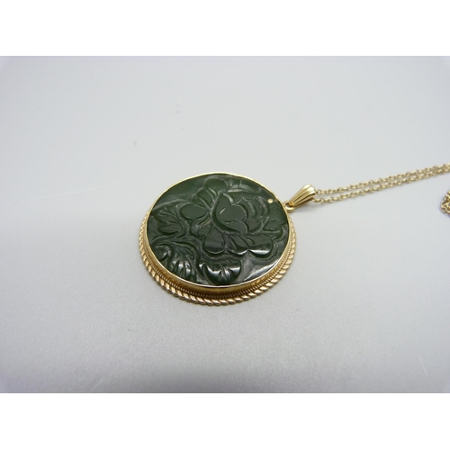 1108 - A 9ct gold mounted carved jade pendant and chain, 29mm diameter, 10g