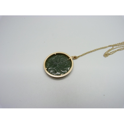 1108 - A 9ct gold mounted carved jade pendant and chain, 29mm diameter, 10g