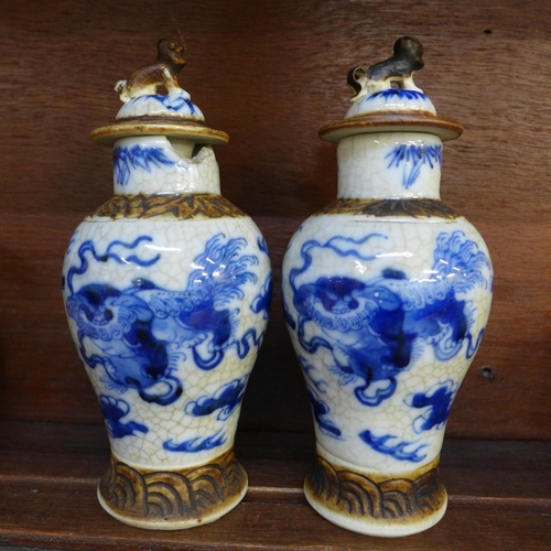 654 - A pair of antique blue and white crackle glaze Chinese vases with figural decorated covers, 16cms, c... 