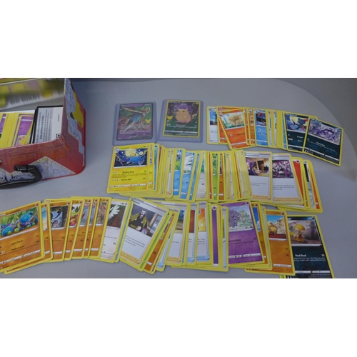 731 - Pokemon cards; a Pokemon collectors tin containing 300 basic Pokemon cards, one full art card in har... 