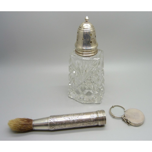 903 - A silver eye glass, a silver topped sugar shaker and a silver handled travel shaving brush