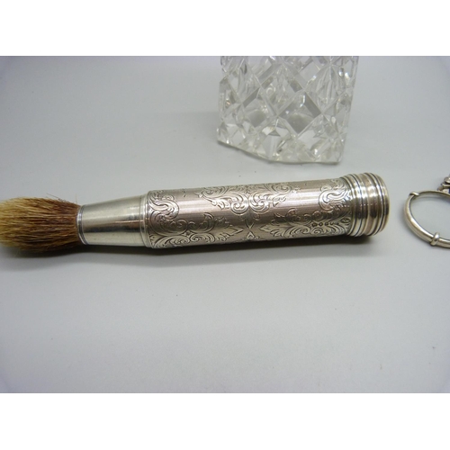 903 - A silver eye glass, a silver topped sugar shaker and a silver handled travel shaving brush