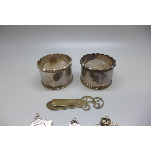 859 - Two silver napkin rings, three silver fobs and a silver book marks, 97g