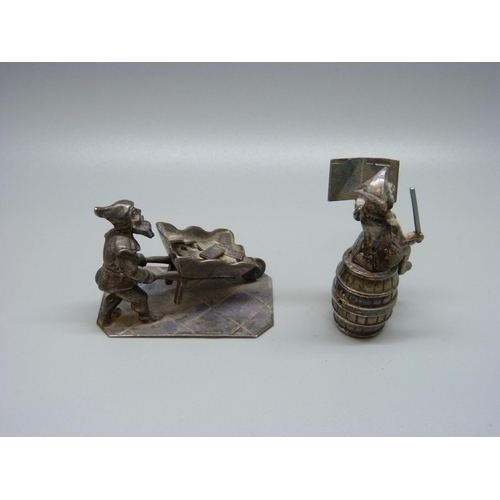 983 - Two silver figures; money seated on a barrel and a  Pixie pushing a wheelbarrow of gold, 107g