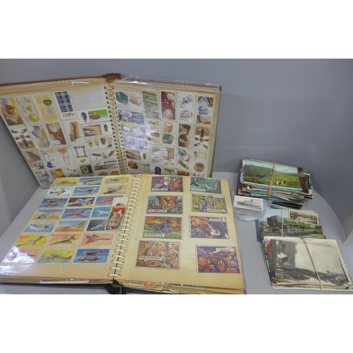 769 - Two albums of cigarette and tea cards and a collection of postcards