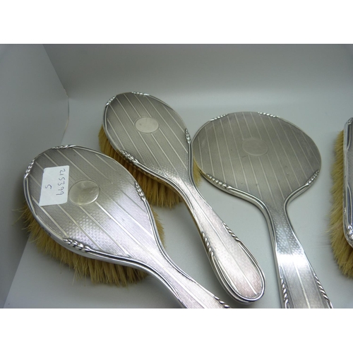 867 - An Art Deco silver backed vanity set; four brushes and a hand mirror