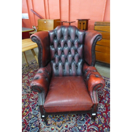 84 - An oxblood red leather Chesterfield wingback armchair