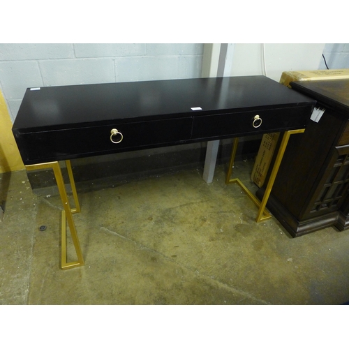 A black two drawer console table with gold legs