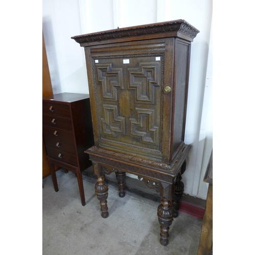 86 - An Elizabethan Revival carved oak geometric moulded cupboard on stand