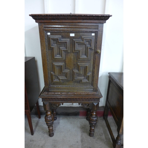 86 - An Elizabethan Revival carved oak geometric moulded cupboard on stand