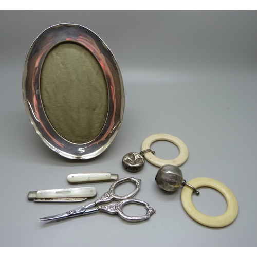 1031 - A silver frame, two rattles, scissors, two silver penknives