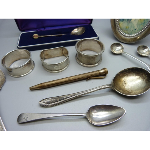 818 - A collection of silver items; oval photograph frame, a pair of Georgian mustard spoons, three napkin... 