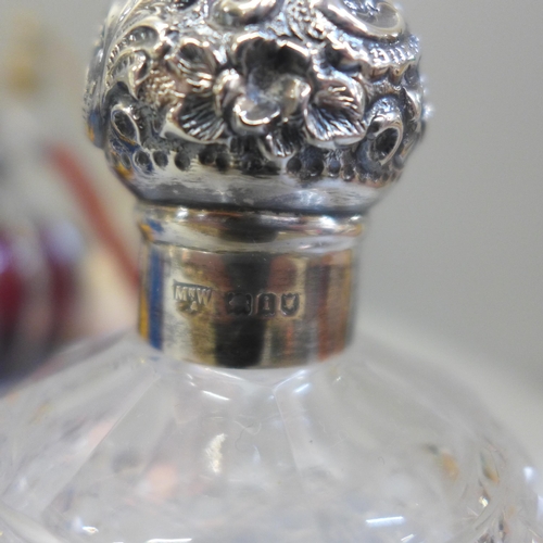 695 - A collection of perfume atomisers and other glass bottles, including one silver topped