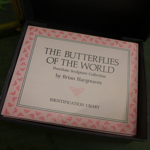 772 - A porcelain sculpture collection, The Butterflies of the World in a glazed cabinet