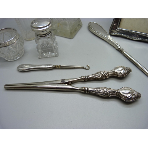 829 - A silver photograph frame, a/f, silver mounted bottles, glove stretchers, etc.