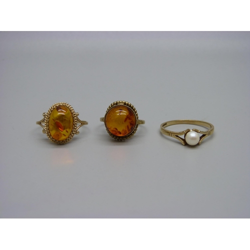 946 - A 9ct gold and amber ring, a 9ct gold and pearl ring and a yellow metal and amber ring marked 333, 6... 