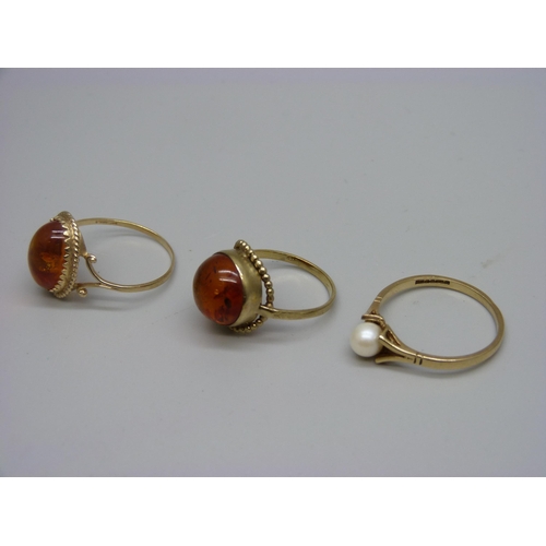 946 - A 9ct gold and amber ring, a 9ct gold and pearl ring and a yellow metal and amber ring marked 333, 6... 